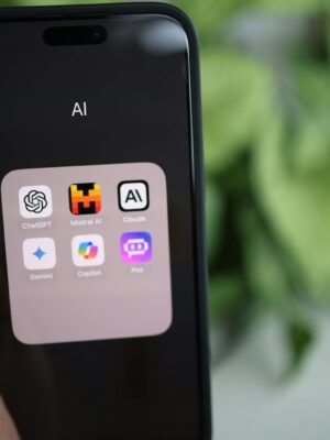 Close-up of a hand holding a smartphone with AI applications on screen.